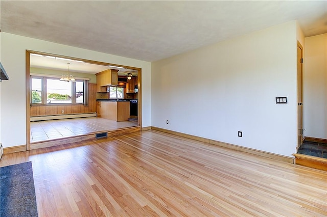 unfurnished living room featuring light wood-type flooring, visible vents, a baseboard radiator, a chandelier, and baseboards