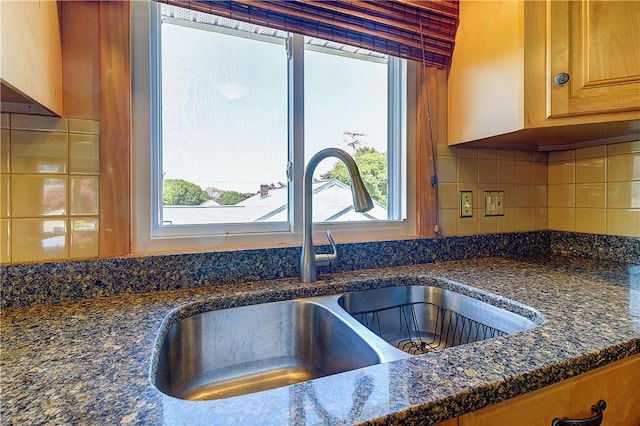 details featuring dark stone counters, backsplash, and a sink