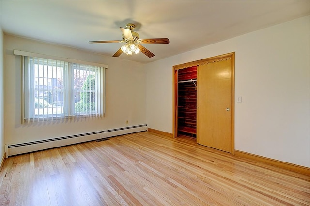 unfurnished bedroom featuring a ceiling fan, baseboard heating, light wood-style flooring, a closet, and baseboards