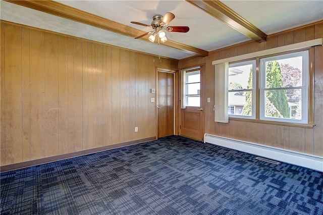 spare room with a ceiling fan, baseboard heating, wooden walls, dark carpet, and beam ceiling
