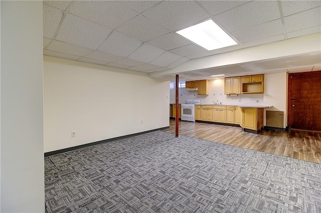 kitchen featuring white range with gas stovetop, baseboards, a sink, light countertops, and carpet floors