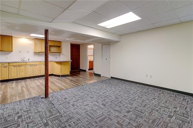 finished basement with baseboards, carpet flooring, and a sink