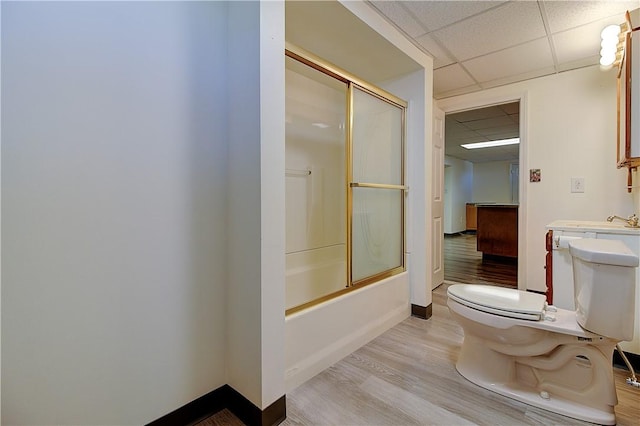 bathroom with toilet, a drop ceiling, baseboards, and wood finished floors