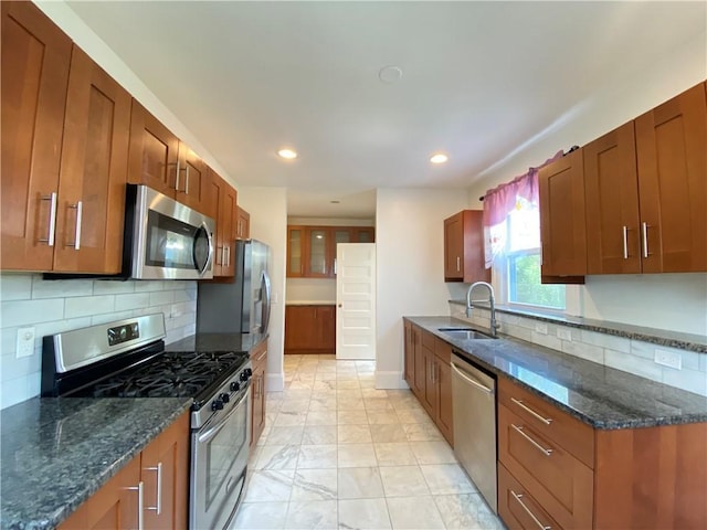 404 Lloyd Ave Unit 408, Providence, RI 02906 - kitchen featuring appliances with stainless steel finishes, a sink, tasteful backsplash, brown cabinets, and dark stone counters