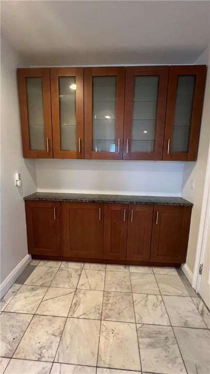 404 Lloyd Ave Unit 408, Providence, RI 02906 - kitchen featuring baseboards, light marble finish floors, glass insert cabinets, and dark stone countertops