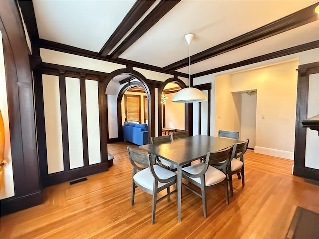 404 Lloyd Ave Unit 408, Providence, RI 02906 - dining space with baseboards, light wood-style floors, arched walkways, and beam ceiling