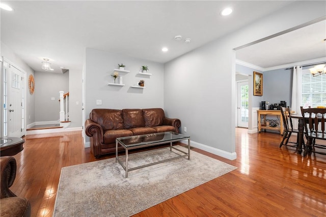 living area featuring baseboards, wood finished floors, a chandelier, recessed lighting, and crown molding