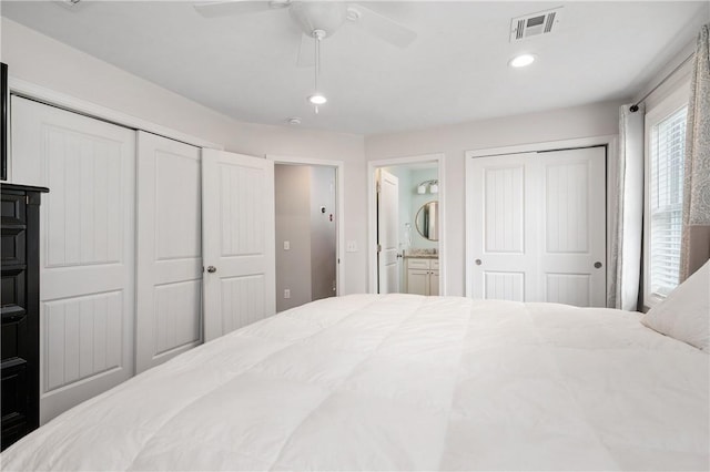 bedroom featuring two closets, ensuite bath, recessed lighting, and ceiling fan