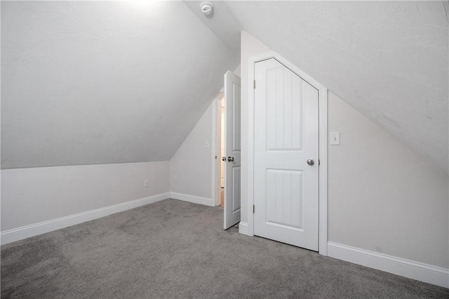 additional living space featuring carpet flooring, lofted ceiling, and baseboards
