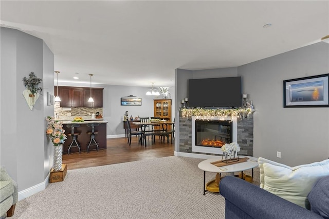 40 Saw Mill Dr Unit 203, North Kingstown, RI 02852 - living area with dark colored carpet, baseboards, a glass covered fireplace, and a chandelier