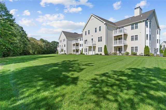 40 Saw Mill Dr Unit 203, North Kingstown, RI 02852 - rear view of house with a chimney, a lawn, and a balcony