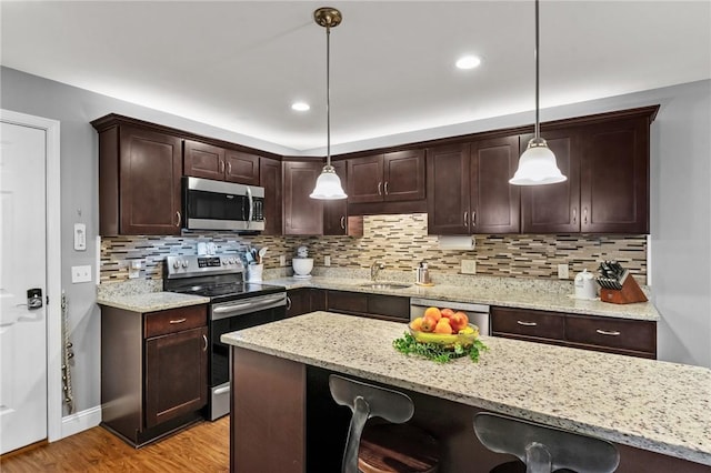 40 Saw Mill Dr Unit 203, North Kingstown, RI 02852 - kitchen featuring appliances with stainless steel finishes, a kitchen bar, dark brown cabinets, light wood-style flooring, and backsplash