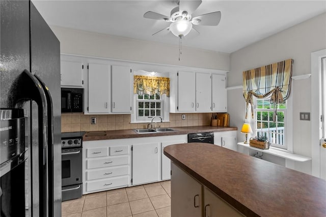 kitchen with black appliances, a sink, dark countertops, and healthy amount of natural light