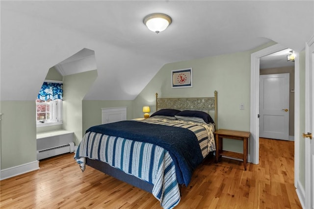 bedroom featuring a baseboard heating unit, wood finished floors, vaulted ceiling, and baseboards