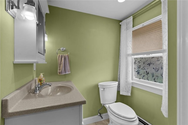half bath with toilet, baseboards, vanity, and tile patterned flooring
