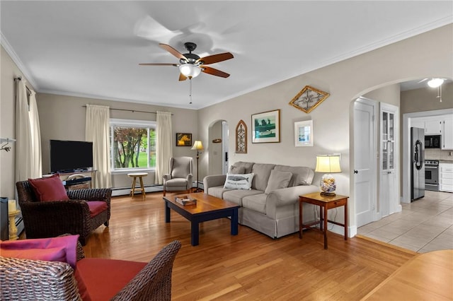 living room with arched walkways, a ceiling fan, a baseboard heating unit, ornamental molding, and light wood finished floors