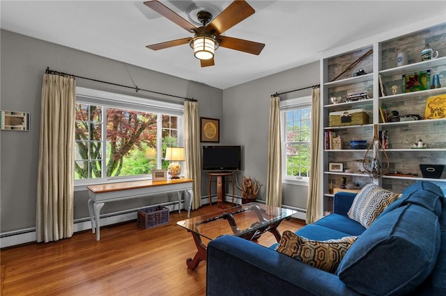 living area with healthy amount of natural light, ceiling fan, and wood finished floors