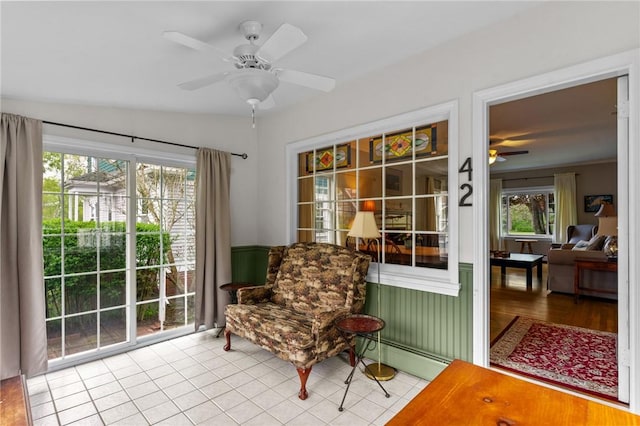living area featuring a ceiling fan, a baseboard radiator, and tile patterned floors