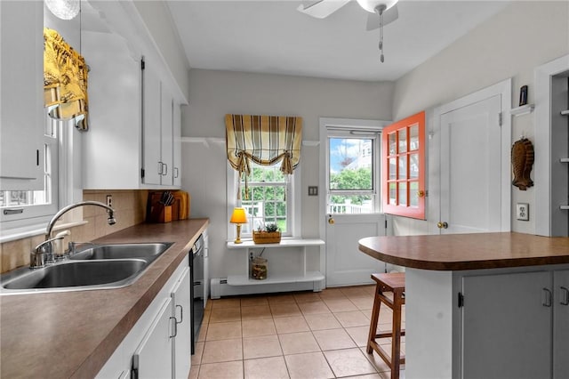 kitchen featuring a sink, dark countertops, healthy amount of natural light, and light tile patterned floors