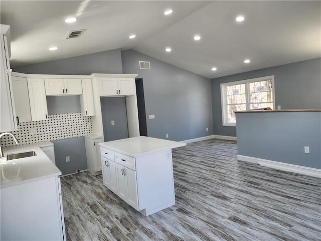 68 Westwood Ave, Cranston, RI 02905 - kitchen with a sink, a kitchen island, light wood-type flooring, white cabinets, and lofted ceiling