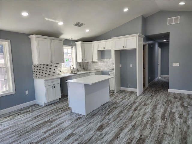 68 Westwood Ave, Cranston, RI 02905 - kitchen featuring a sink, a center island, vaulted ceiling, white cabinetry, and light wood-style floors