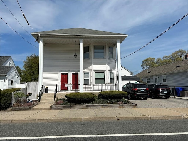 greek revival inspired property featuring covered porch and concrete driveway