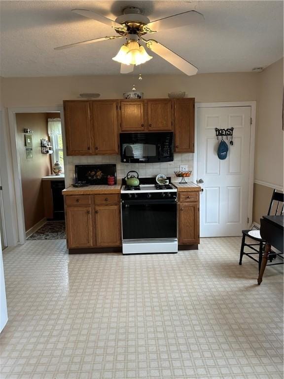 kitchen featuring black microwave, gas range oven, brown cabinets, and tasteful backsplash