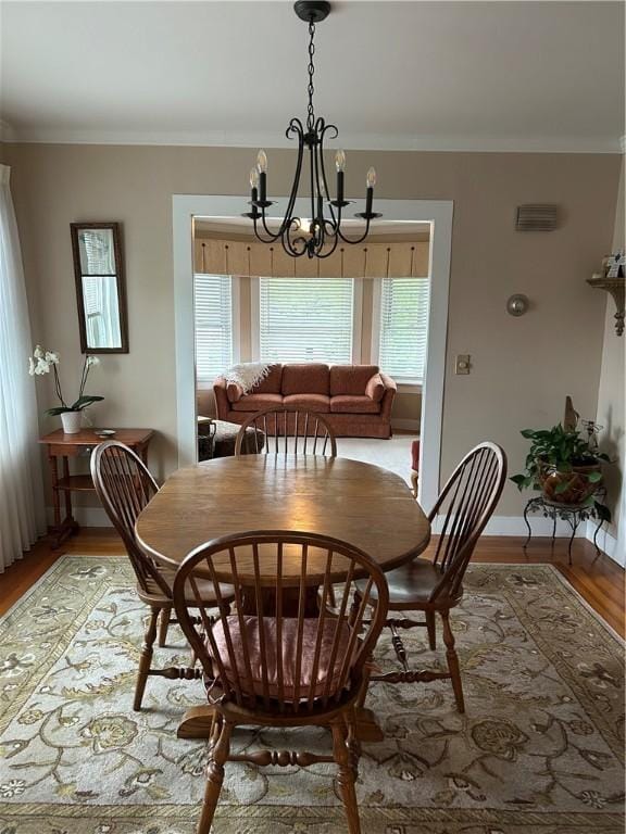 dining area featuring a chandelier, crown molding, light wood finished floors, and baseboards