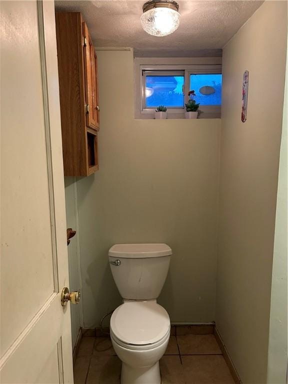 bathroom with tile patterned flooring, toilet, baseboards, and a textured ceiling