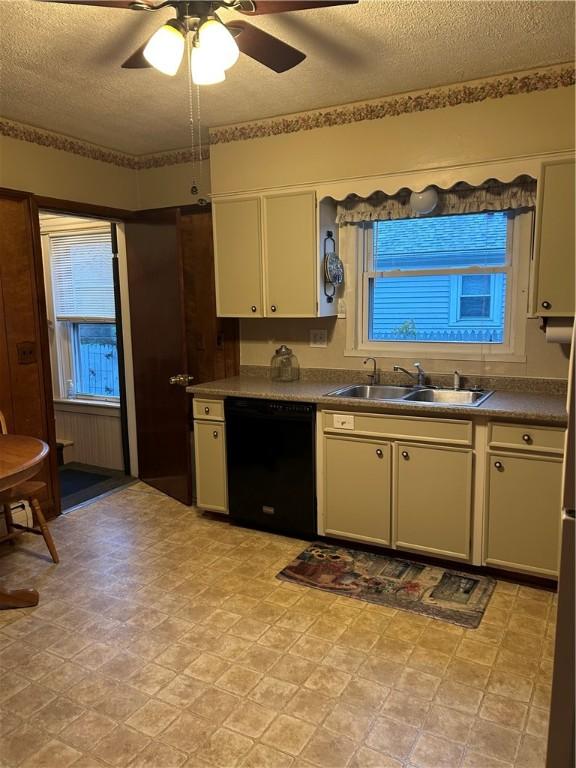 kitchen with black dishwasher, a sink, a textured ceiling, a ceiling fan, and dark countertops