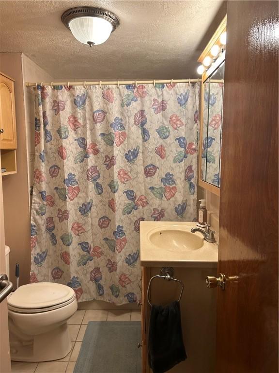 bathroom with tile patterned flooring, a textured ceiling, toilet, a shower with shower curtain, and vanity