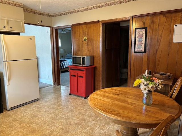 kitchen with freestanding refrigerator, stainless steel microwave, light floors, and a textured ceiling