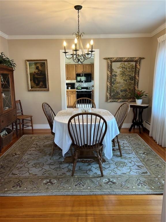 dining space with a chandelier, a baseboard radiator, wood finished floors, baseboards, and ornamental molding