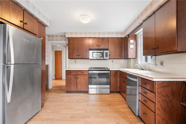 11 Homestead St, Smithfield, RI 02917 - kitchen featuring appliances with stainless steel finishes, a sink, light wood-style floors, light countertops, and brown cabinets