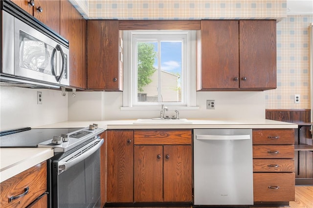 11 Homestead St, Smithfield, RI 02917 - kitchen with appliances with stainless steel finishes, a sink, light countertops, wallpapered walls, and brown cabinets