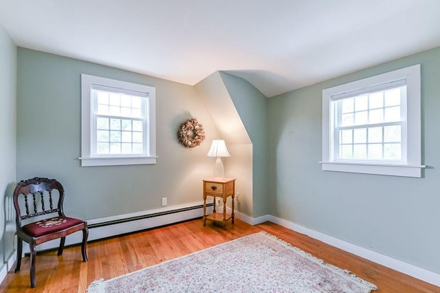 living area with wood finished floors, a baseboard radiator, and baseboards