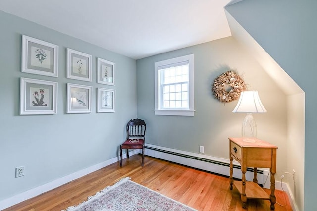 sitting room with a baseboard radiator, wood finished floors, and baseboards