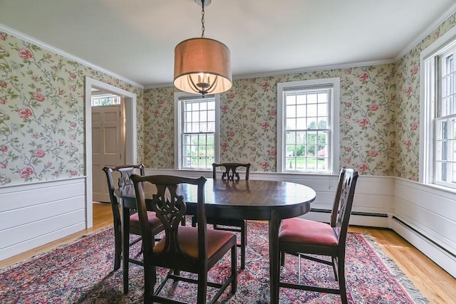 dining room with plenty of natural light, light wood-style floors, crown molding, a wainscoted wall, and wallpapered walls