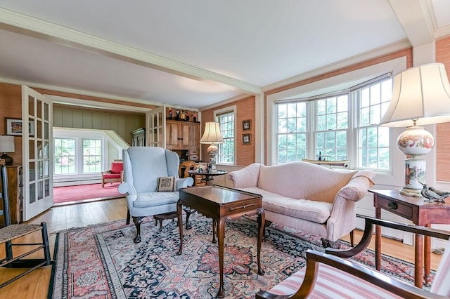 living room featuring wood finished floors, ornamental molding, and a baseboard heating unit
