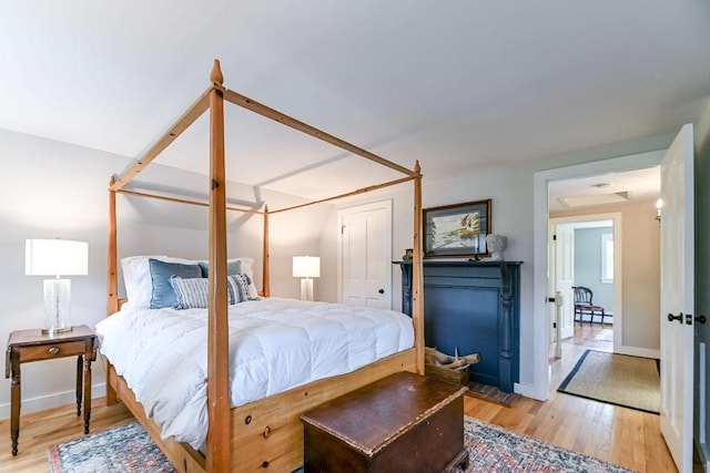 bedroom with light wood-style flooring, a baseboard heating unit, and baseboards