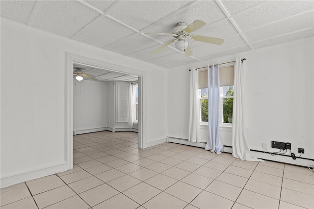 spare room with ceiling fan, baseboards, light tile patterned floors, a baseboard radiator, and a drop ceiling