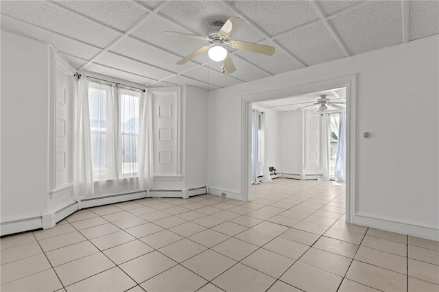 empty room with ceiling fan, light tile patterned floors, baseboards, and a paneled ceiling