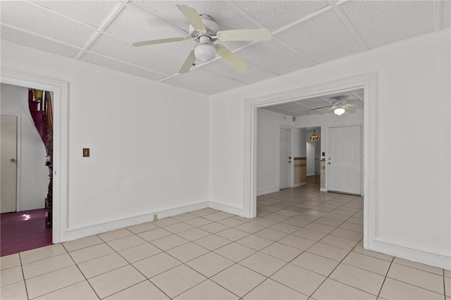 unfurnished room with light tile patterned flooring, a ceiling fan, and baseboards