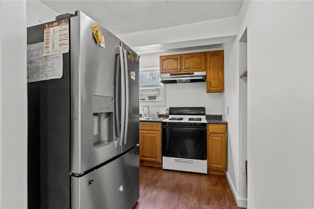 kitchen featuring white gas range oven, stainless steel fridge, under cabinet range hood, a sink, and dark wood-style floors