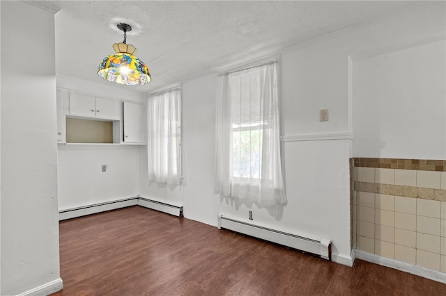 spare room featuring a baseboard heating unit, dark wood-style floors, and a textured ceiling