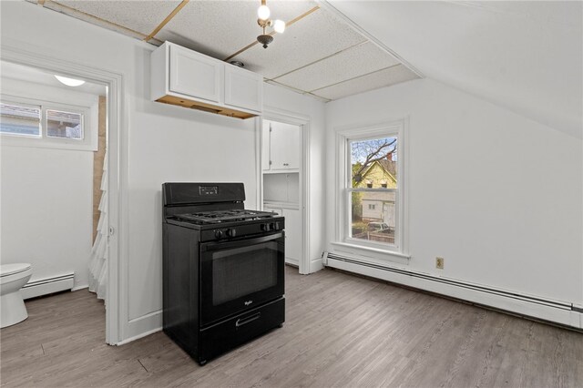 kitchen with gas stove, a baseboard heating unit, white cabinetry, light wood-style floors, and vaulted ceiling
