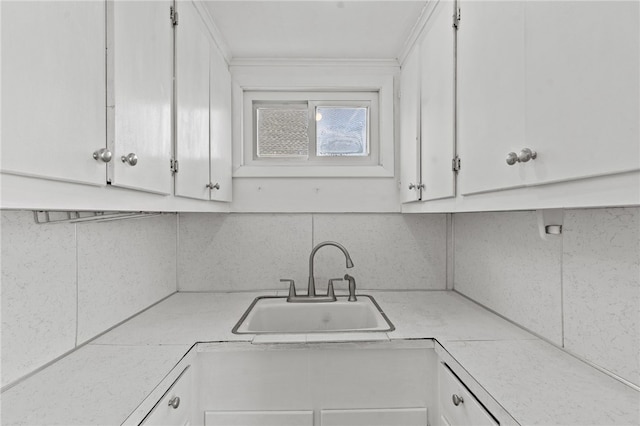 kitchen featuring a sink, light countertops, white cabinetry, and crown molding