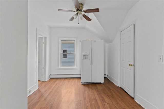 unfurnished bedroom featuring white fridge with ice dispenser, a baseboard heating unit, wood finished floors, baseboards, and lofted ceiling