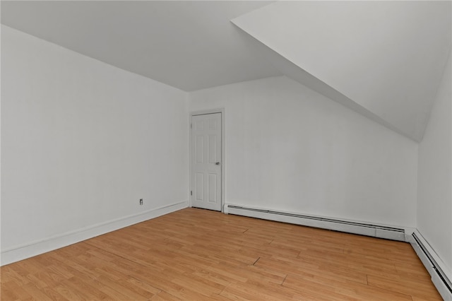 bonus room featuring a baseboard heating unit, light wood finished floors, vaulted ceiling, and baseboards