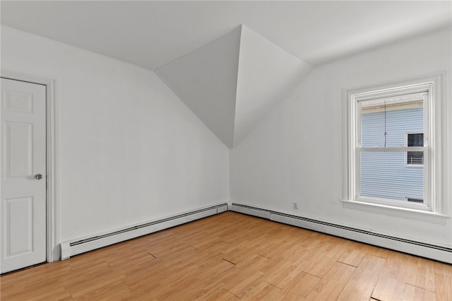 additional living space with light wood finished floors, vaulted ceiling, and a baseboard radiator